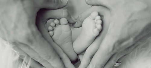 family with baby feet making heart showing love and security